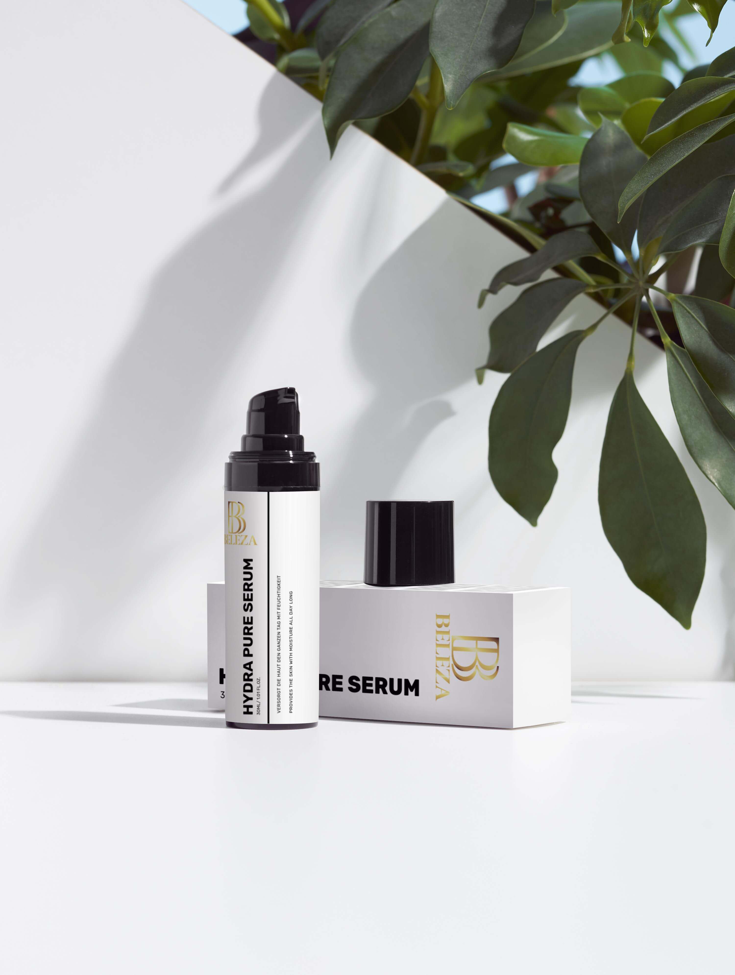 Hydra Pure Serum bottle with box, surrounded by green leaves, showcasing its hydrating benefits and sleek design.